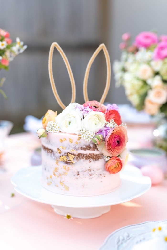 joli naked cake recouvert d'une couche légère de crème au beurre rose et décoré de fleurs, cake topper oreilles de lapin