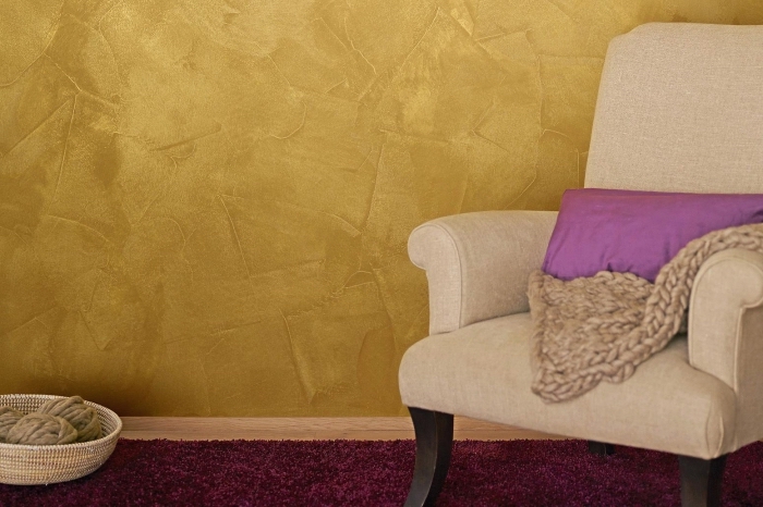 revêtement mural à effet sablé, décoration salon aux murs jaune moutarde, modèle fauteuil beige avec pieds noirs