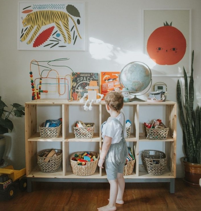 meuble bois bas avec des paniers rangement jouets, affiches muraux décoratifs animaux et plantes, jouets enfant