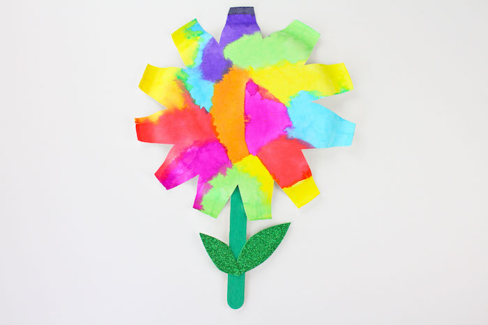 fleur colorée a faire soi meme et papier couleurs aquarelle et tige en batonnet de glace et des feuilles vertes pailletées