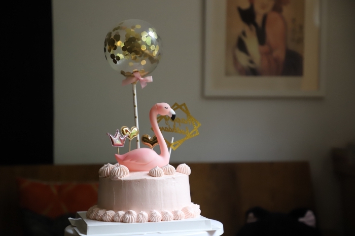 image gateau anniversaire pour fille décoré avec une figurine flamant rose, un ballon transparent à confettis dorés et des cake-toppers festifs