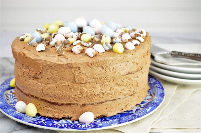 un gateau au chocolat au lait sur le thème de pâques, gâteau génoises au cacao recouvert de crème au beurre et chocolat décoré d’œufs de pâques en chocolat