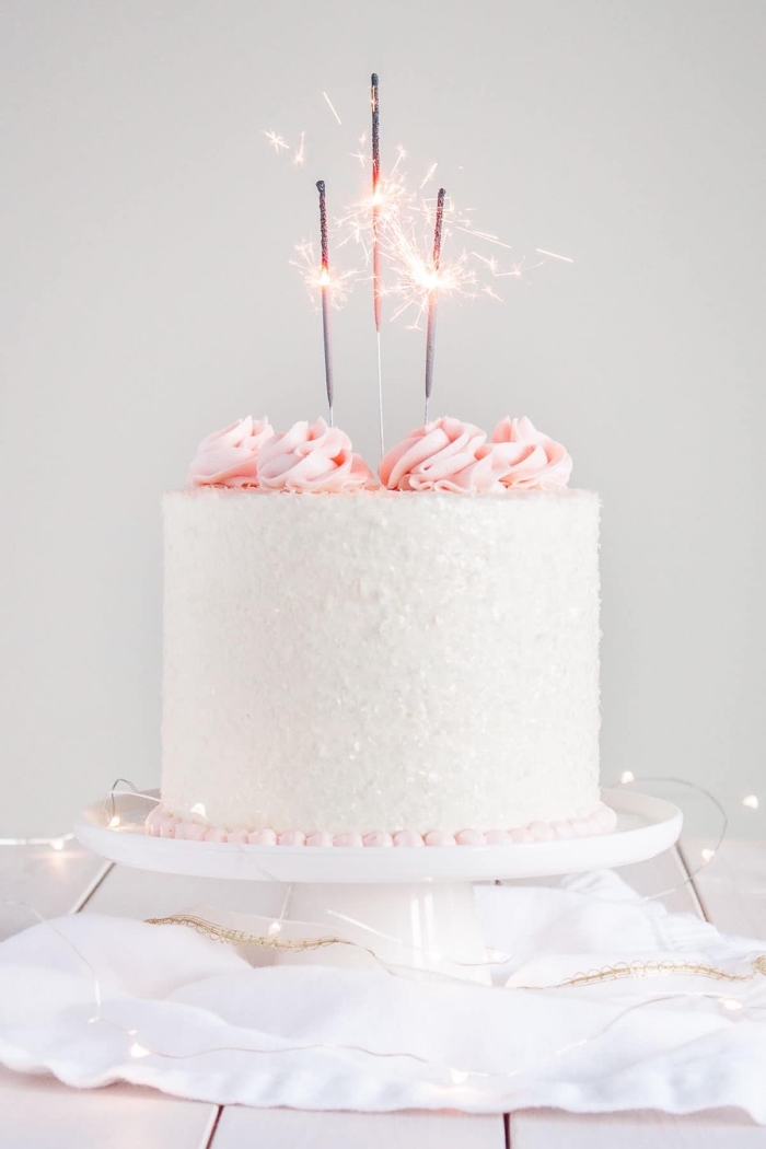 gâteau à la champagne au glaçage de crème beurre décoré avec des roses en glaçage et des bougies fontaines