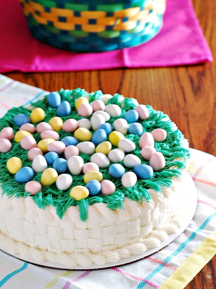 joli gâteau façon panier paques au glaçage de crème au beurre effet tissé, décoré d'herbe en glaçage vert et de petits œufs en chocolat