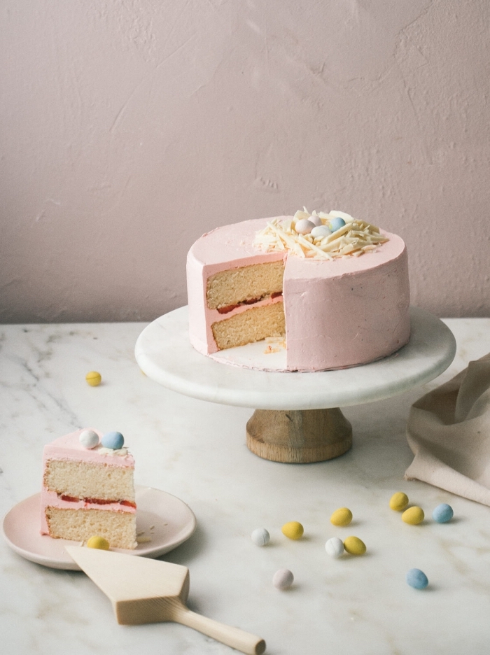 idées de desserts pour pâques, gateau nid de paques traditionnel à la vanille et à la fraise recouvert de glaçage rose de crème au beurre avec un nid en chocolat blanc