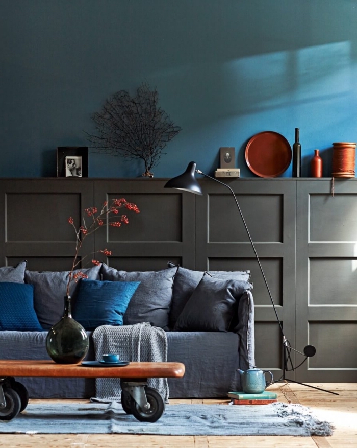 idée habillage mur intérieur bois pour sublimer le bas des murs, panneaux décoratifs à caissons couleur gris anthracite posés au mur du salon derrière le canapé munis avec un espace rangement dessus