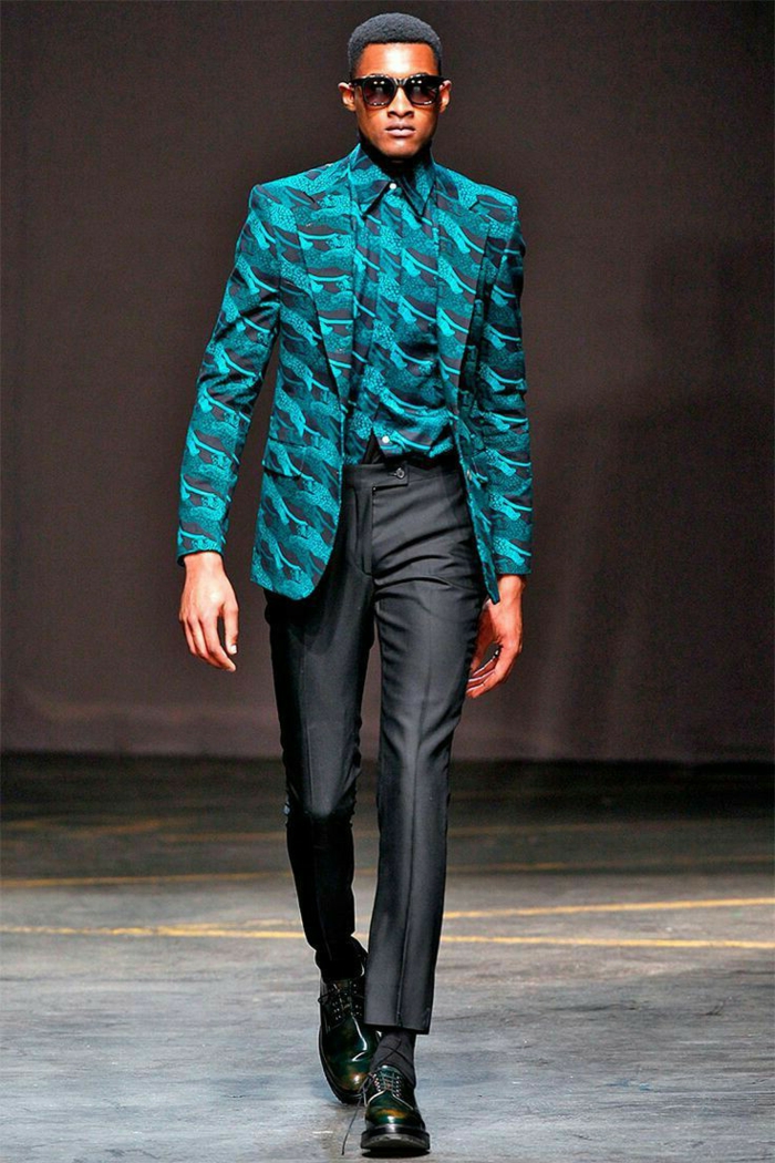 modèle africainportant une tenue africaine pour homme, pantalon noir et chemise turquoise, veste motifs ethniques, lunettes de soleil