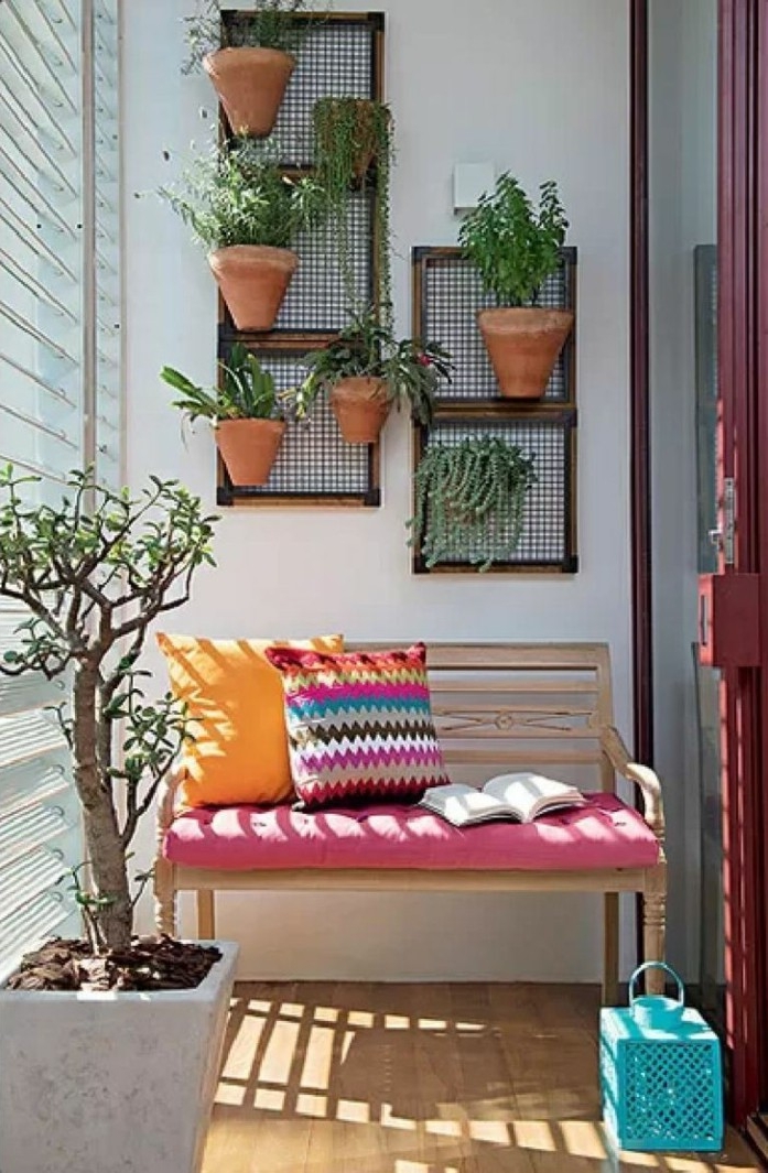 deco balcon simple en banc de bois décoré de coussins colorés, revêtement sol bois, mur végétal de pots fleuris