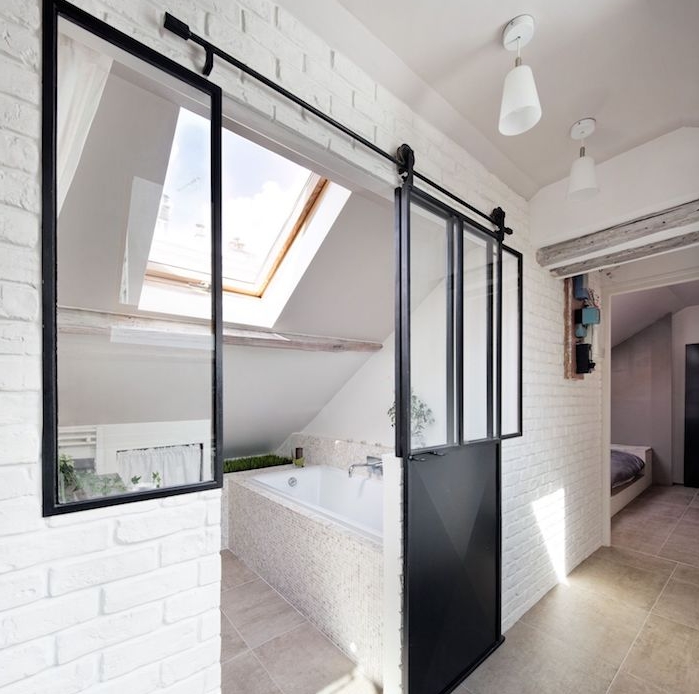 mini salle de bain 2m2 sous pente, porte galandage noire, murs blancs et carrelage gris clair, fenêtre de toit