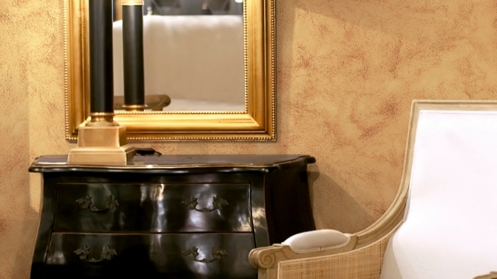 quel revêtement mural pour un salon, déco de pièce aux murs sablés de nuance dorée avec meubles or et noir