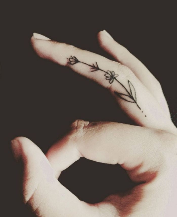 tatouage sur le doigt majeur représentant une fleur minimaliste qui s'étend sur toute la longueur du doigt