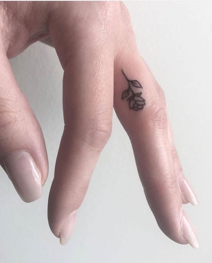 une petite rose au design discret et féminin réalisée sur le côté du doigt majeur, idée d'emplacement pour un tatouage petite rose 
