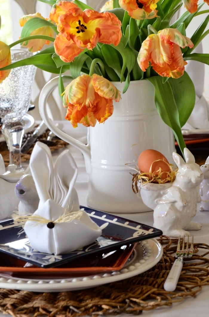 décoration de table de pâques de tulipes, de porte-oeufs lapins en céramique, serviette en forme de lapin paques arrangé dans une belle assiette noire et blanc