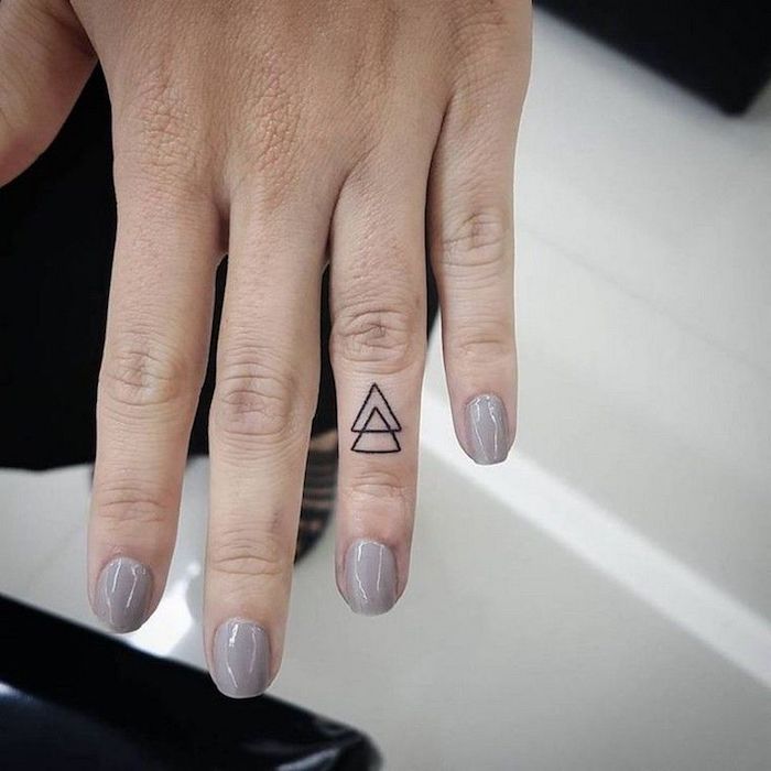 dessins de tatouage doigt minimaliste et géométriques représentant deux petits triangles entrelacés tatoués sur l'annulaire