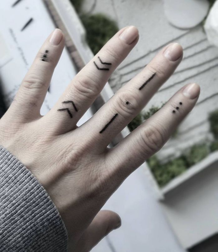 tatouage sur les doigts aux inspirations tribales représentant de petites flèches, des points et des lignes
