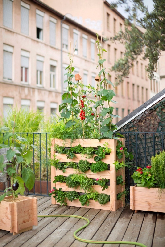 une jardiniere balcon haute en bois qui accueille plusieurs types de plantes