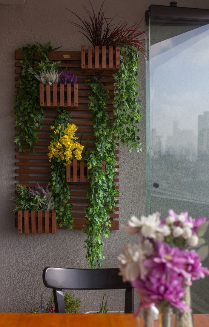 une structure murale avec des lattes en bois et des bacs à planter pour créer un jardin vertical gain de place sur le balcon