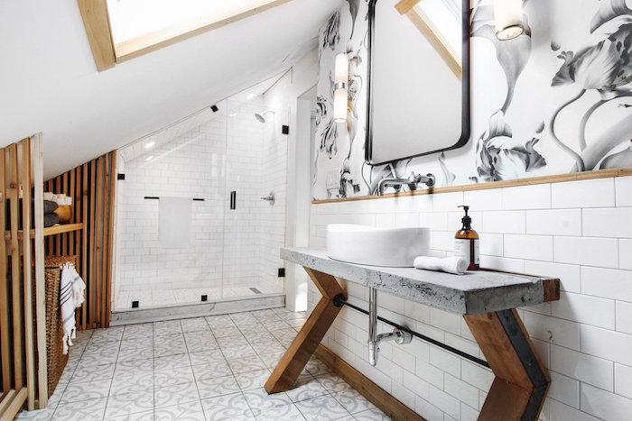 agencement salle de bain intéressant avec une douche sous pente et carrelage blanc, meuble vasque avec pieds de bois et plan de travail éton, accents boisés et pan de mur papier peint salle de bain