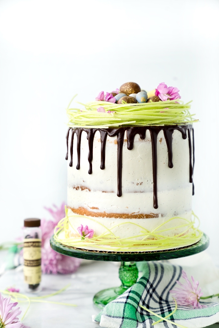 gâteau à étages au glaçage coulant de chocolat avec une jolie décoration d'herbe de pâques comestible et de petits oeufs en chocolat