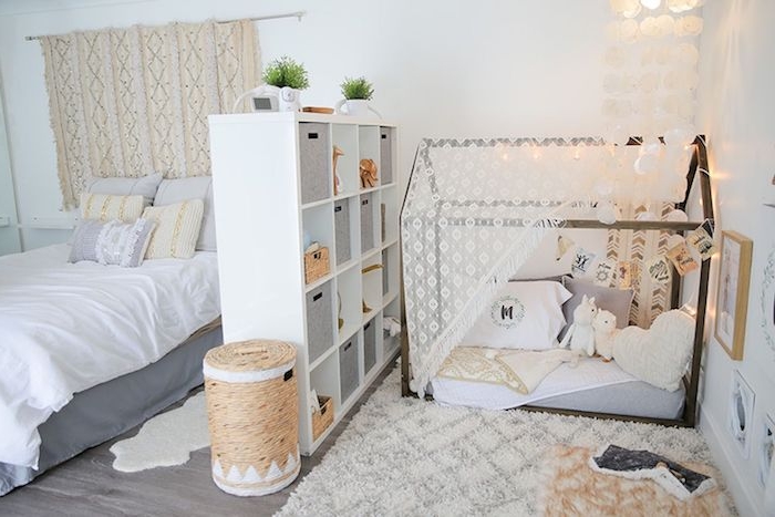 amrenagement chambre adulte avec un espace montessori séparé d une étagère, lit cabane au sol décoré de jouets et coussins, lit avec linge gris et blanc