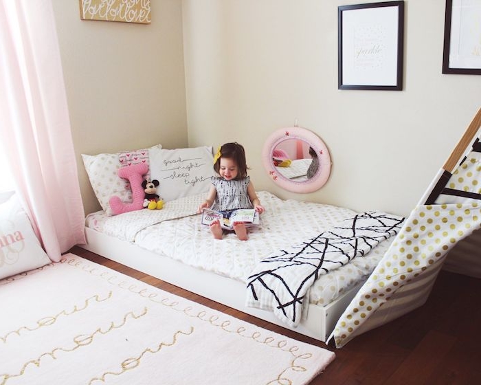 lit au sol montessori avec un tipi cabane sur parquet marron, tapis blanc à texte, murs couleur beige, amenagement chambre fille