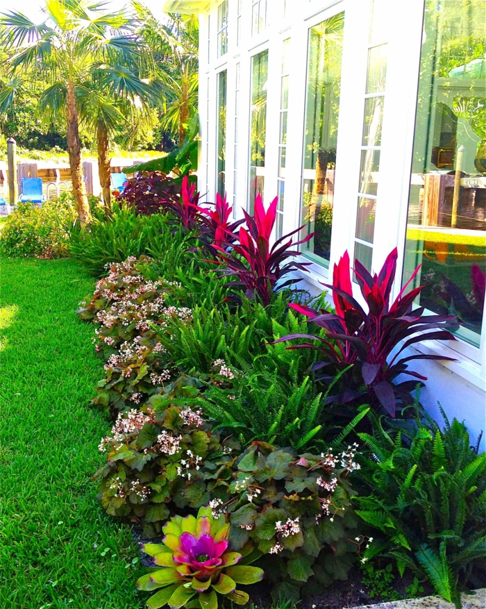 massif fleuri devant une maison plain pied, pelouse verte, palmiers, modele de parterre de fleurs