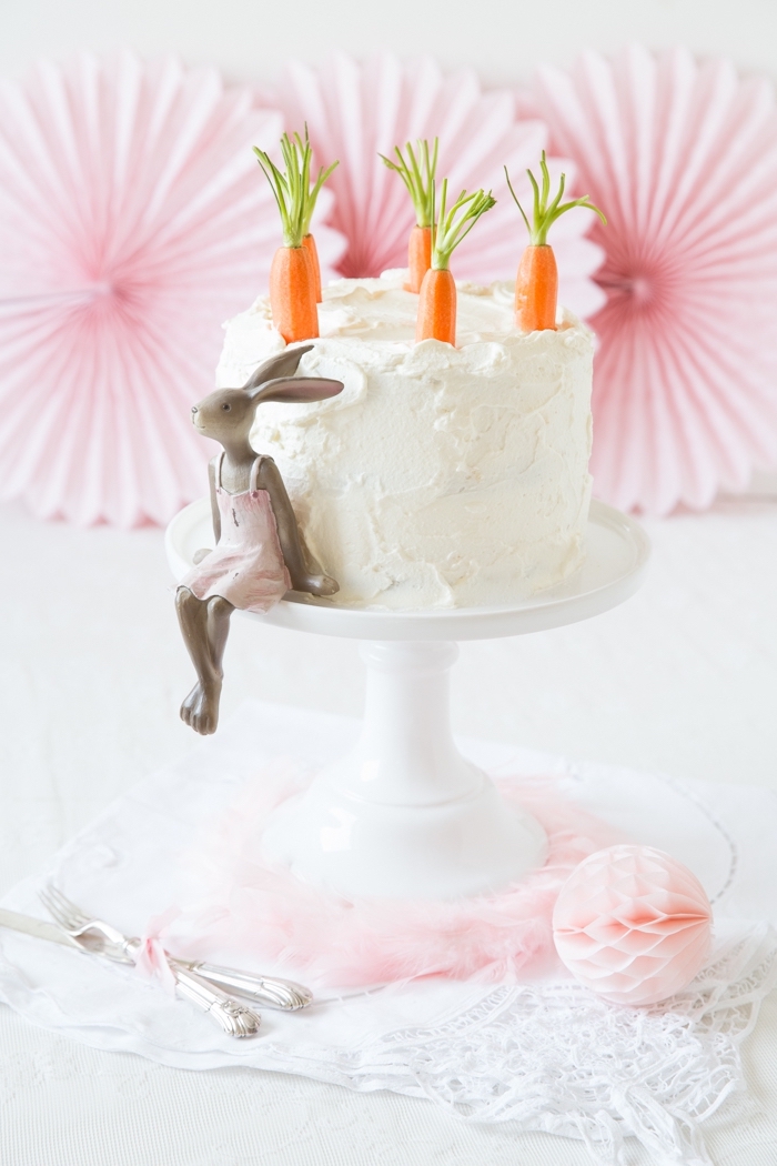 dessert de paques traditionnel, savoureux gâteau aux carottes recouvert au glaçage de crème au beurre décoré de carottes en pâte à sucre et d'une figurine lapin mignon