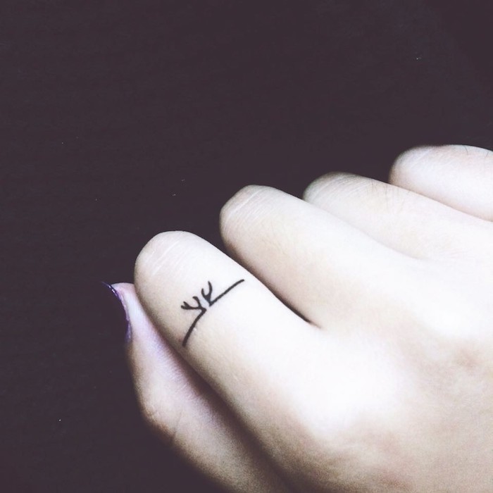 petit tatouage doigt sur l'annulaire façon bague à motif bois de cerf, choix d'un motif et emplacement pour un tatouage discret
