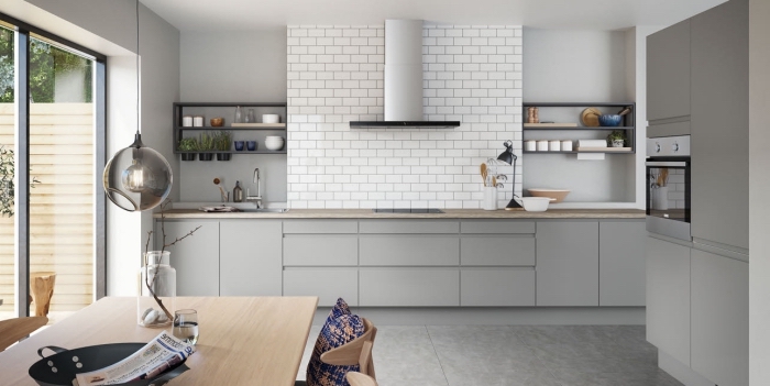 cuisine spacieuse au plafond blanc et plancher gris clair aménagée avec armoires gris clair et plan de travail bois