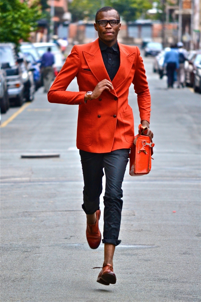 pantalon gris, chaussures de sport rouges, sac rouge, veste rouge, chemise bleu foncée, homme dans la rue