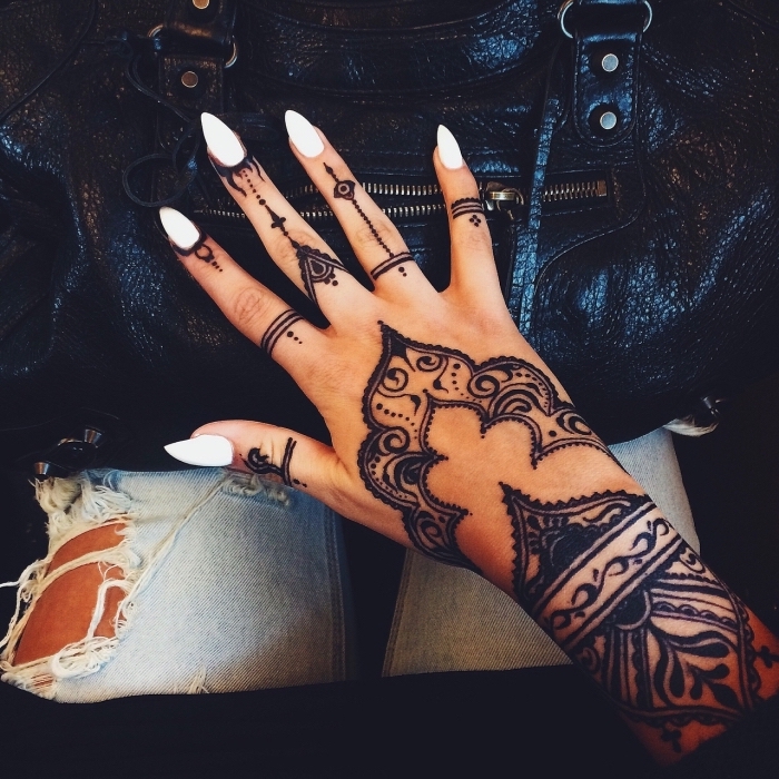 tatouage main femme au henné noir aux motifs traditionnels orientaux dessinés sur tous les doigts, le poignet et la main