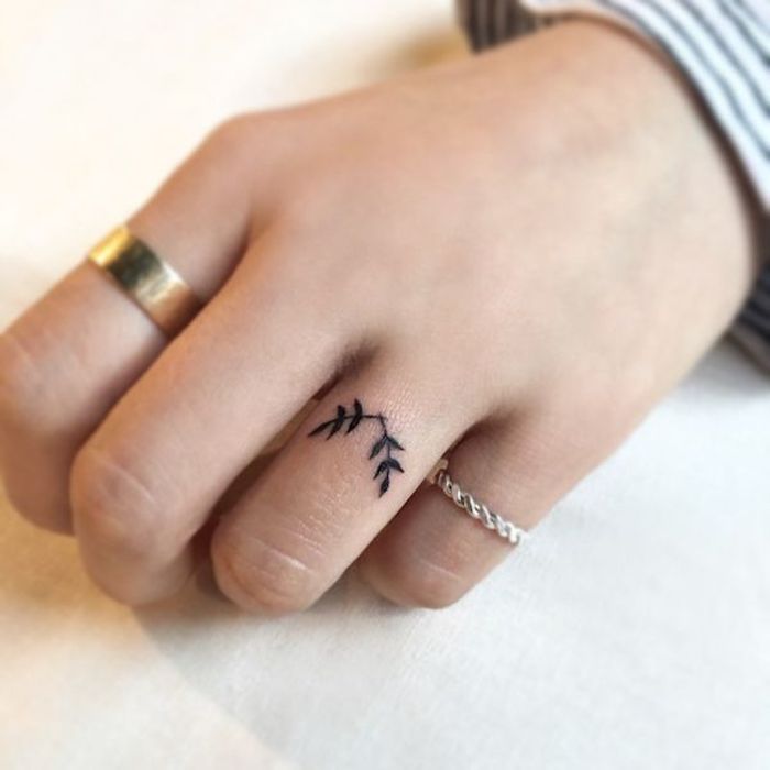 tatouage doigt femme au design discret et féminin représentant deux petites branches tatouées façon bague sur l'annulaire