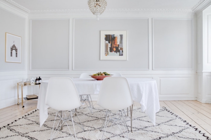 une salle à manger blanche de style vintage scandinave avec des moulures d'esprit classique qui donne du relief aux murs sans alourdir la déco, habillage mur intérieur bois tendance