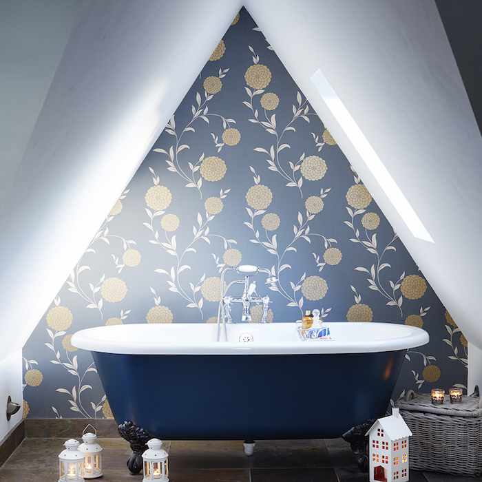 baignoire bleu nuit au milieu d une salle de bain mansarée avec mur d accent bleu à motifs floraux, lanternes lumineuses, panier de rangement