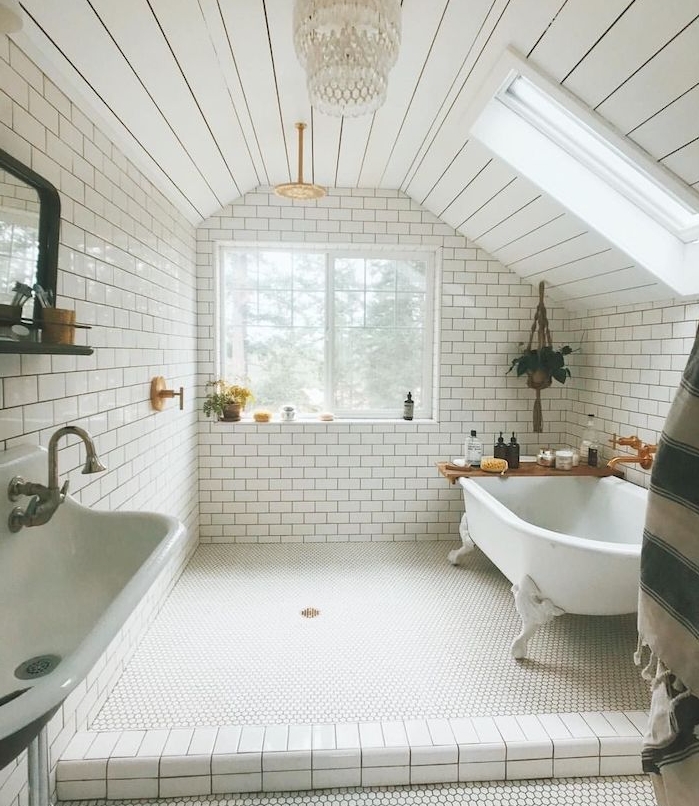 carrelage metro blanc dans une salle de bain mansardée style retro cic, baignoire blanche, pot de fleur suspendu macramé, lustre élégant