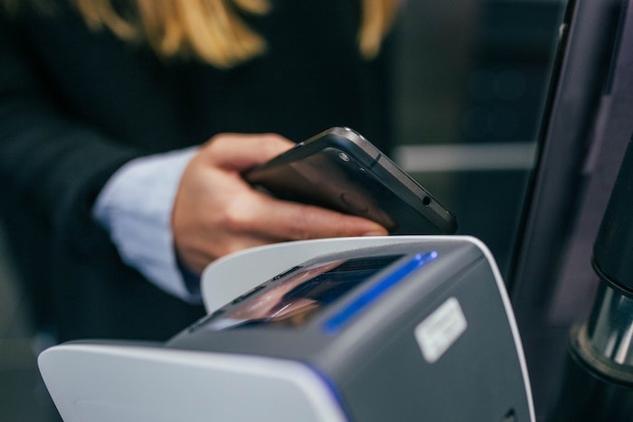 femme avec portable dans la main en traine de faire un paiement de téléphone