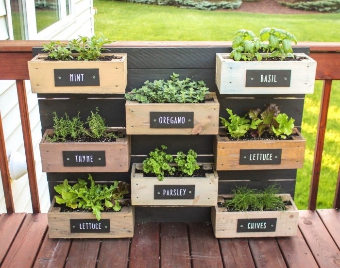des aromatiques plantées dans une jardinière en palette avec des bacs à planter à niveaux différents, idée pour aménager un petit jardin en hauteur avec une palette recyclée