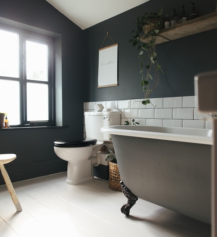 salle de bain aux murs gris anthracite, baignoire à poser grise, soubassement carrelage blanc, parquet blanchi, wc noir et blanc design