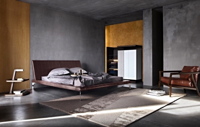 idée comment décorer une chambre masculine aux murs à texture béton, modèle de grand lit avec tête en cuir marron