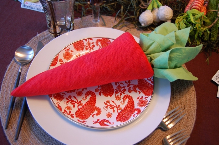 un pliage serviette paques en forme de carotte réalisée avec deux nappes de couleur rouge et verte