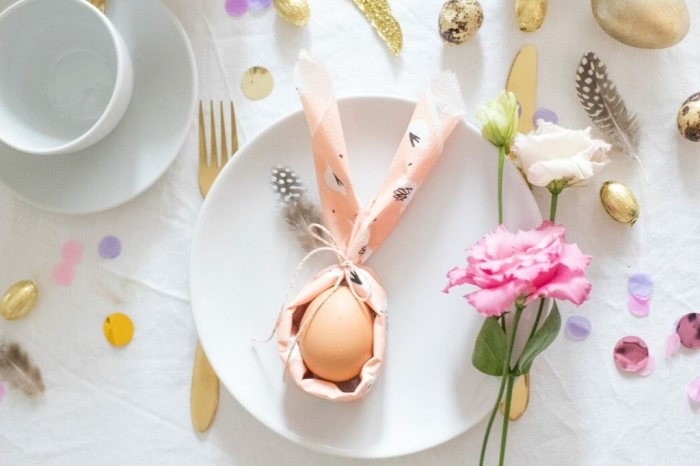 modèle de pliage serviette lapin autour d'un oeuf, décoration de table de pâques douce en blanc, or et rose