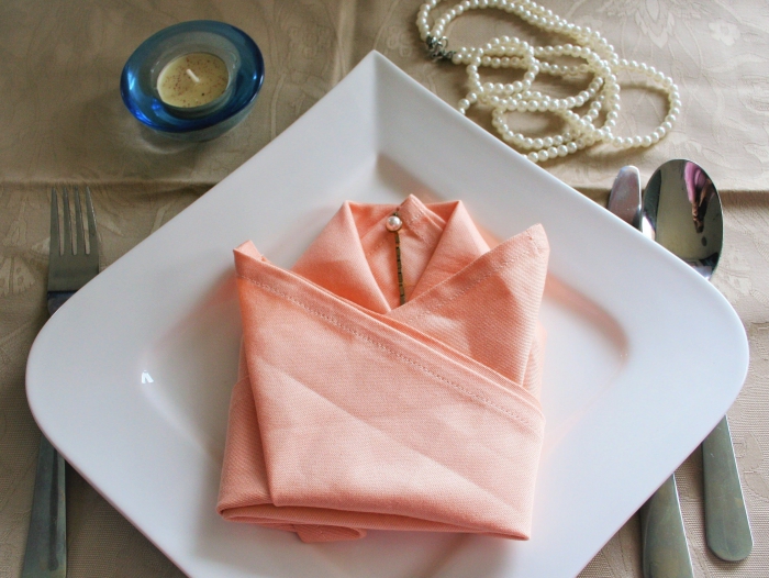 déco de table de fête élégante avec une serviette couleur corail pliée en tulipe, idée de pliage serviette paques en forme de fleur