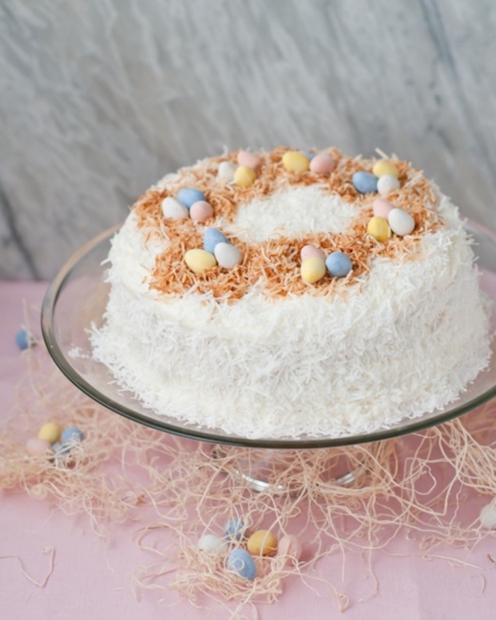 gâteau nid de pâques à la noix de coco décoré de petits oeufs en chocolat en couleurs pastel et de noix de coco grillée