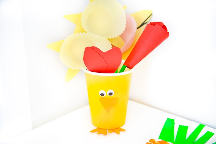 gobelet en plastique poussin aux yeux mobiles et bec de papier rempli de fleurs de papier colorés avec papier simple et caissettes à muffins
