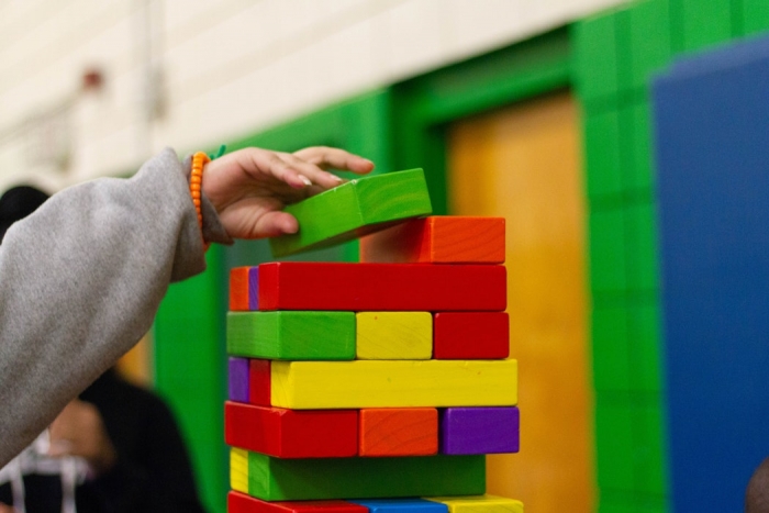 Comment peur un robot apprend à jouer à Jenga, enfant et ses briques colorés, main d'enfant qui pose une pièce de Jenga 