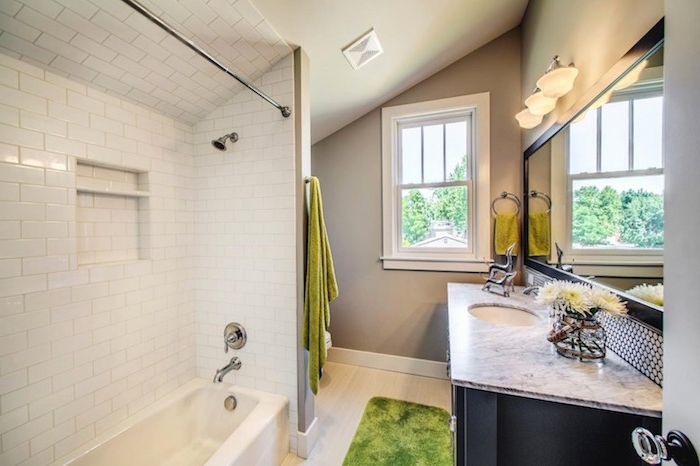 salle de bain douche et baignoire avec carrelage blanc, sol bois clair, meuble salle de bin gris foncé avec plan de travail marbre, miroir horizontal, murs gris
