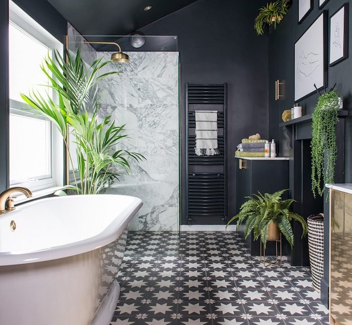 salle de bain noire design avec carrelage noir et blanc original, baignoire rose et plantes salle de bain vertes, douche avec paroi verre et mur de marbre, accents laiton