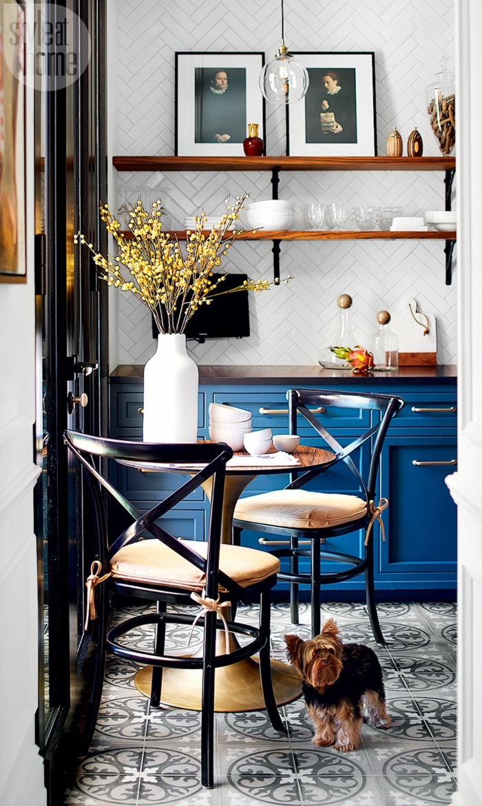 cuisine en bleu et blanc, étagères en bois, vase blanc avec fleurs, petite table ronde, meuble bistrot bleu
