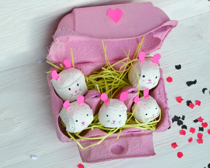 petits lapins en papier mâché cachés dans un carton à oeufs peint rose, oreilles roses et herbe artificielle
