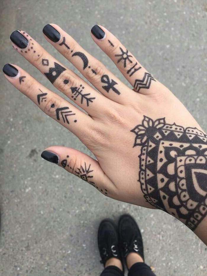 tatouage main au henné composé d'un dessin mandala réalisé sur le poignet et de motifs tribaux géométriques tatoués sur les doigts